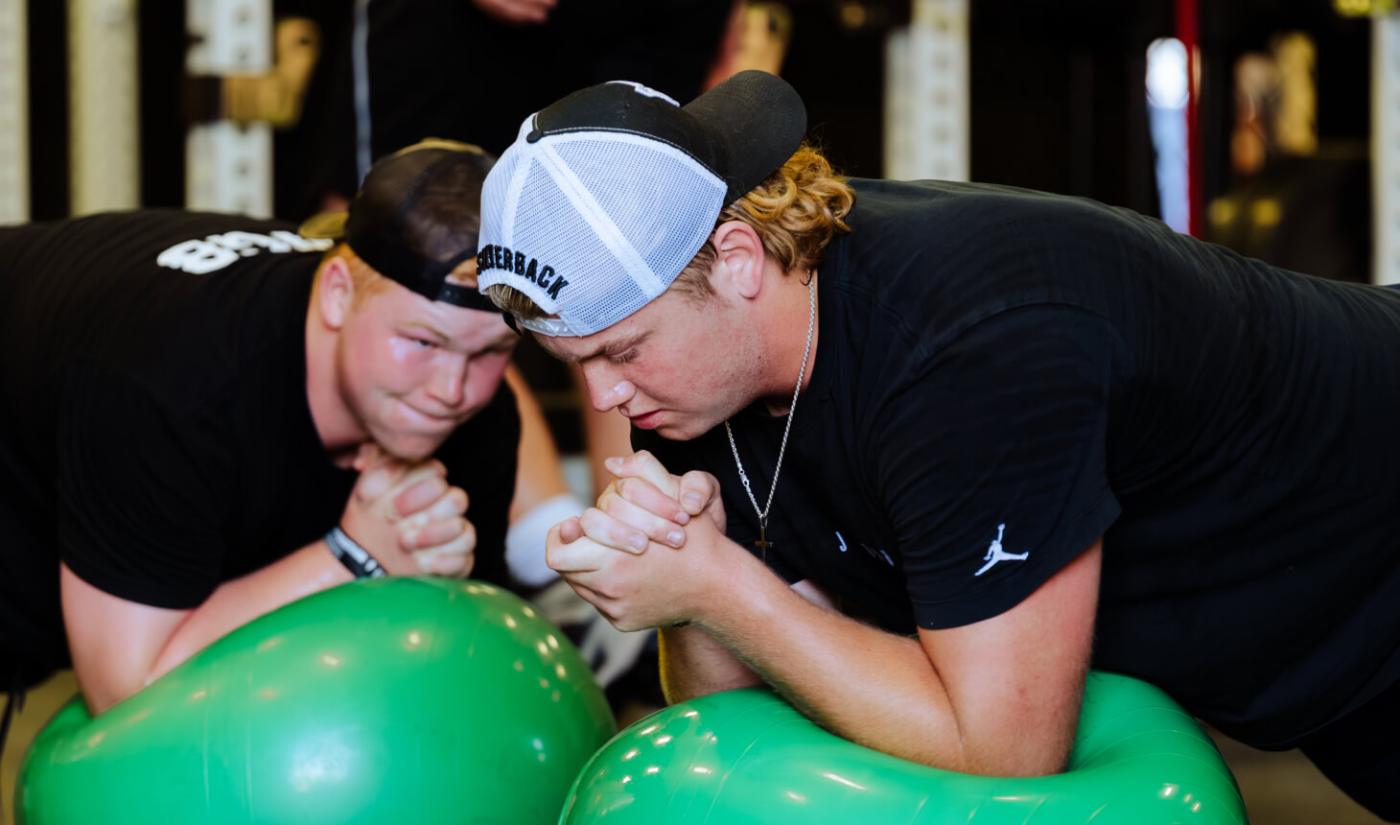 Two athletes brace against each other on stability balls